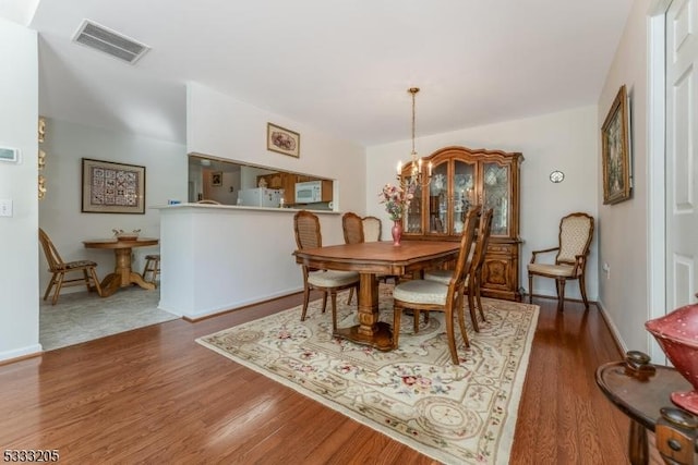 dining space with dark wood-type flooring and a chandelier