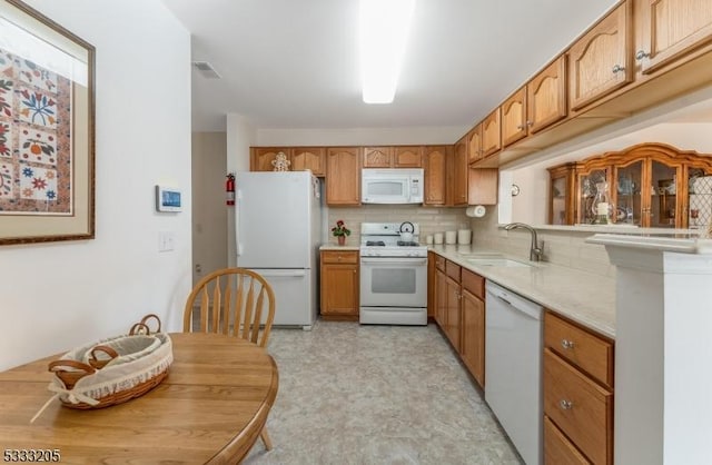 kitchen featuring sink, backsplash, and white appliances