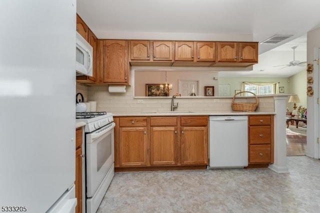 kitchen featuring ceiling fan with notable chandelier, white appliances, decorative backsplash, sink, and kitchen peninsula