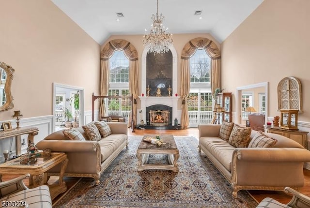 living room with a large fireplace, a wealth of natural light, an inviting chandelier, and a towering ceiling