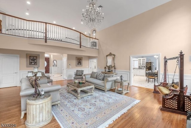 living room featuring light hardwood / wood-style floors, a high ceiling, and an inviting chandelier