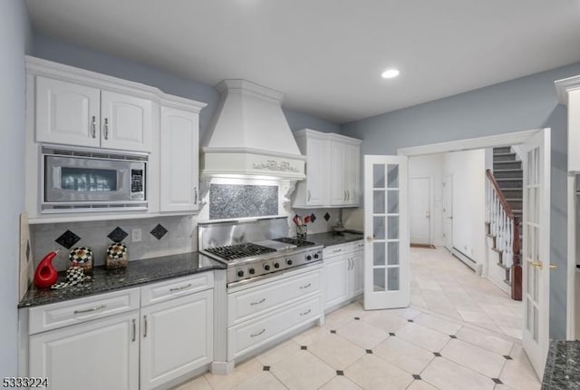 kitchen featuring appliances with stainless steel finishes, custom exhaust hood, backsplash, and white cabinetry