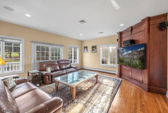 living room featuring light wood-type flooring, plenty of natural light, and a baseboard radiator