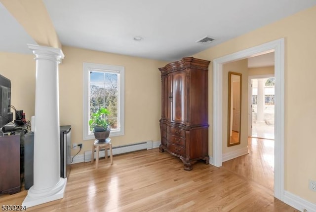 sitting room featuring light hardwood / wood-style floors, a baseboard radiator, ornate columns, and a healthy amount of sunlight