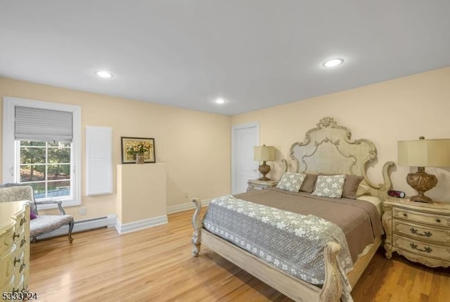 bedroom with baseboard heating and light hardwood / wood-style floors