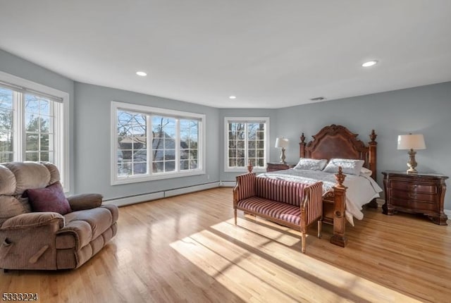 bedroom with light hardwood / wood-style floors and a baseboard radiator