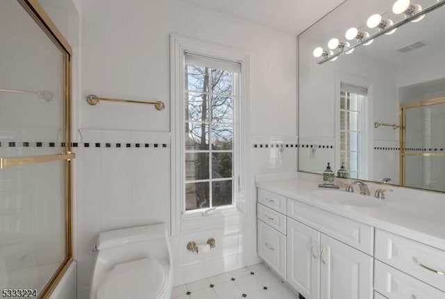 full bathroom featuring toilet, tile walls, enclosed tub / shower combo, and vanity