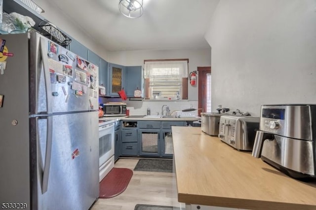 kitchen with backsplash, light wood-type flooring, appliances with stainless steel finishes, and sink