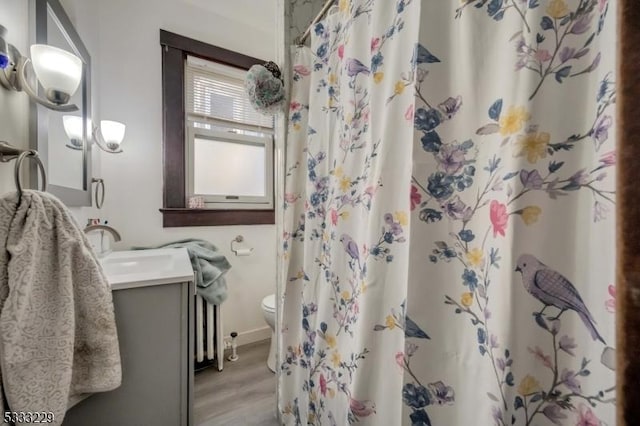 bathroom featuring toilet, walk in shower, hardwood / wood-style floors, and vanity