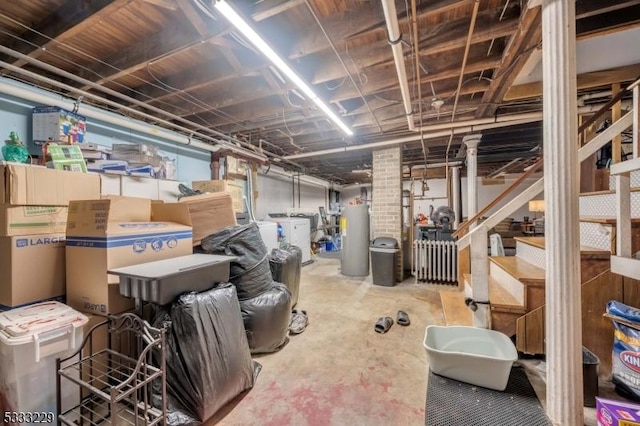 basement with radiator, water heater, and washer / dryer