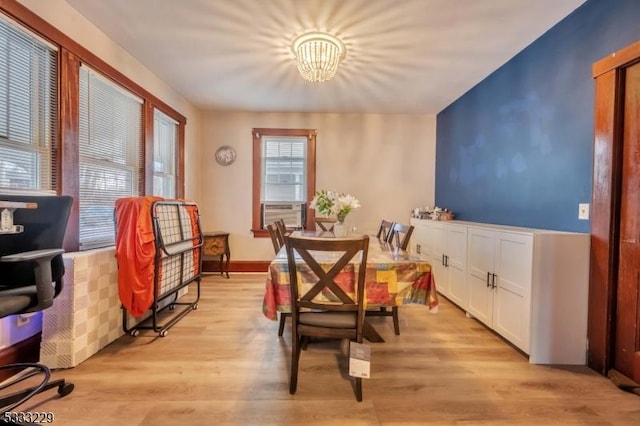 dining area featuring cooling unit, a notable chandelier, and light hardwood / wood-style flooring