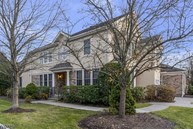 view of front of house featuring stone siding, a front lawn, and stucco siding