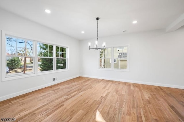 unfurnished dining area with a healthy amount of sunlight, light wood-type flooring, and an inviting chandelier