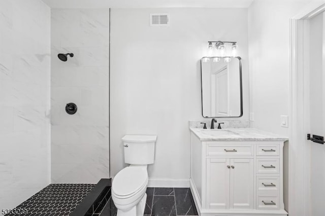 bathroom with toilet, vanity, and tiled shower