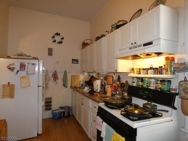 kitchen with wood-type flooring, white refrigerator, gas range, and white cabinetry