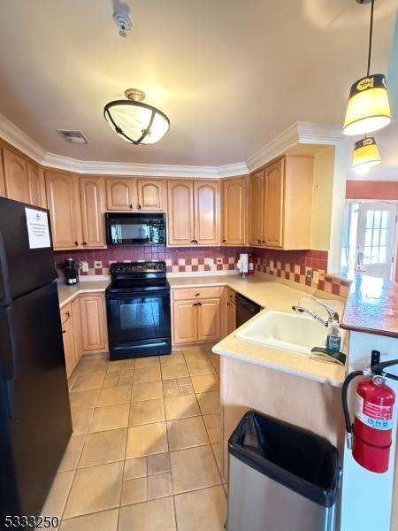 kitchen with light brown cabinets, decorative light fixtures, light tile patterned flooring, black appliances, and sink