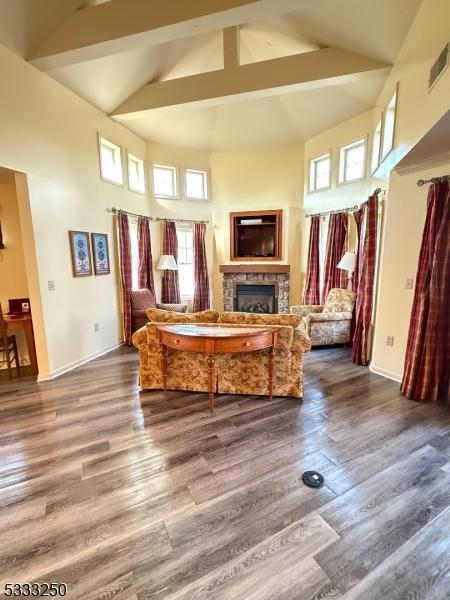 interior space featuring high vaulted ceiling, dark hardwood / wood-style floors, beamed ceiling, and a fireplace