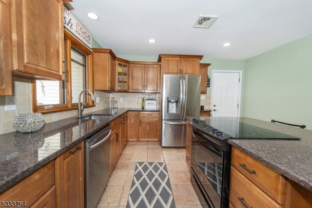 kitchen with sink, light tile patterned floors, dark stone counters, stainless steel appliances, and decorative backsplash