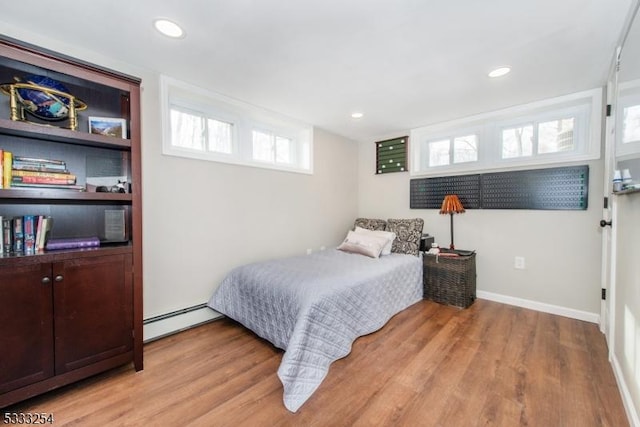 bedroom with a baseboard heating unit and light wood-type flooring