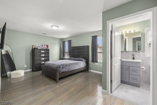 bedroom featuring ensuite bathroom, multiple windows, and light hardwood / wood-style flooring