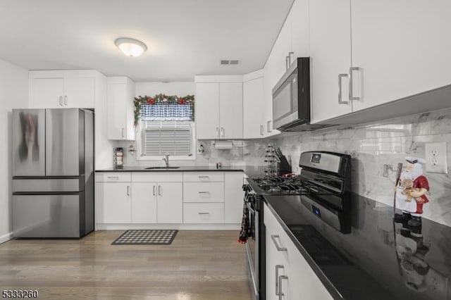 kitchen featuring backsplash, dark hardwood / wood-style floors, sink, white cabinetry, and stainless steel appliances