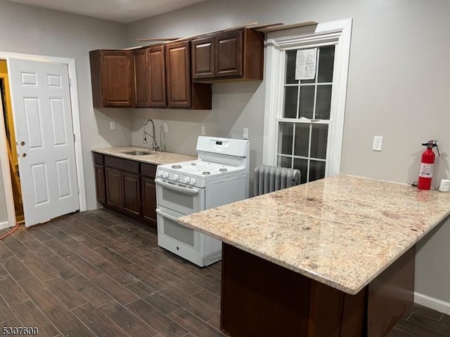 kitchen featuring radiator, range with two ovens, sink, kitchen peninsula, and dark brown cabinets