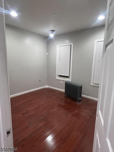 spare room with dark hardwood / wood-style floors and radiator heating unit