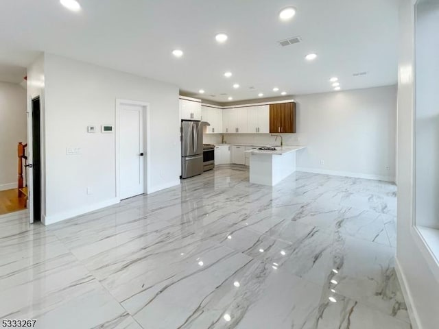 kitchen with appliances with stainless steel finishes, white cabinetry, a kitchen island, and sink