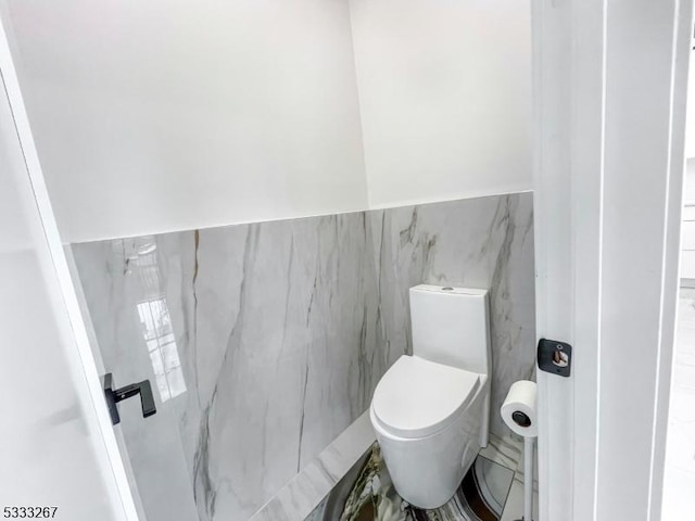 bathroom with toilet and tile walls