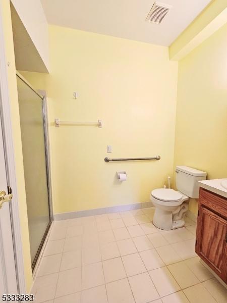 bathroom with toilet, a shower with door, tile patterned floors, and vanity