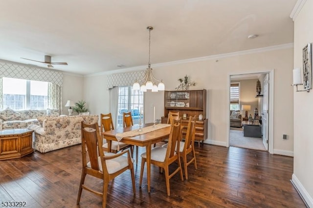 dining room featuring dark wood-type flooring, ornamental molding, and ceiling fan with notable chandelier