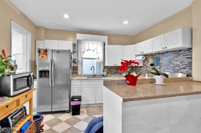 kitchen with stainless steel appliances, decorative backsplash, white cabinetry, and sink