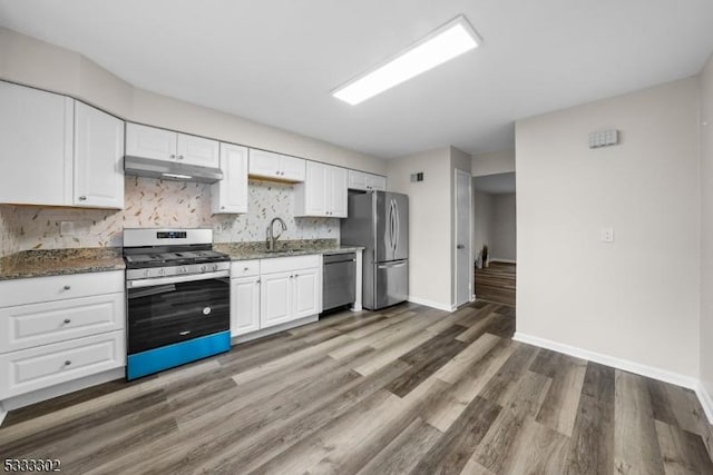 kitchen with stainless steel appliances, white cabinetry, and dark stone countertops