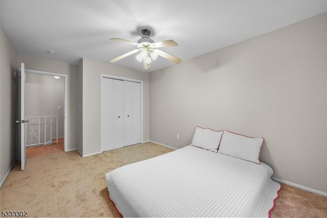 bedroom with ceiling fan, light carpet, and a closet