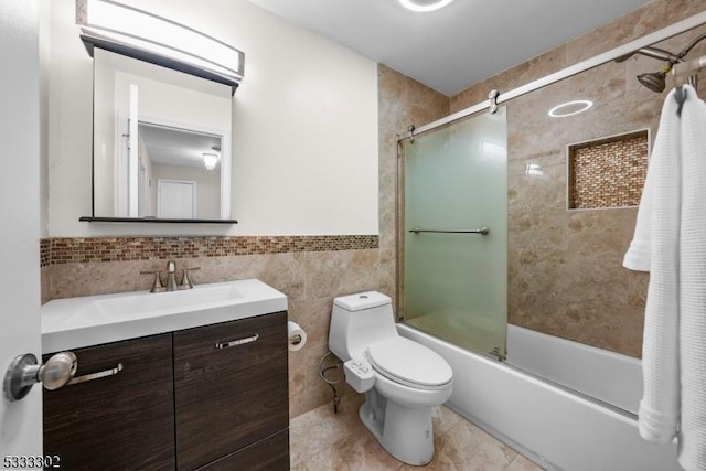 full bathroom with tile patterned floors, toilet, combined bath / shower with glass door, tile walls, and vanity