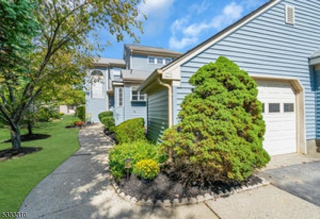 view of side of property featuring a garage and a lawn