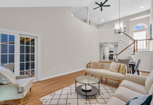 living room featuring high vaulted ceiling, light hardwood / wood-style flooring, and ceiling fan with notable chandelier