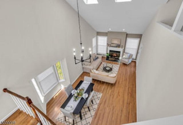 living room featuring hardwood / wood-style flooring, a skylight, and an inviting chandelier