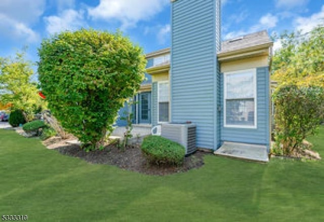 rear view of house featuring cooling unit and a yard