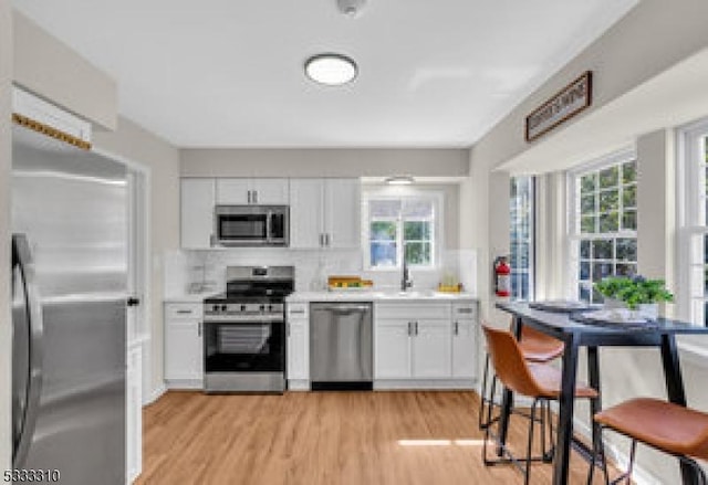 kitchen with white cabinets, appliances with stainless steel finishes, and a wealth of natural light