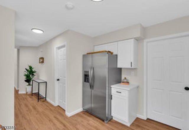 kitchen featuring white cabinets, stainless steel fridge, and light hardwood / wood-style flooring