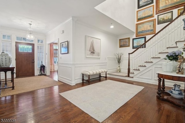 foyer entrance with an inviting chandelier, ornamental molding, and dark hardwood / wood-style flooring