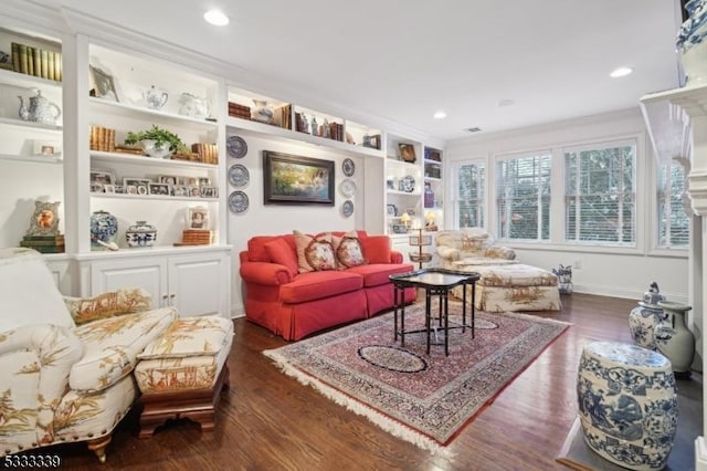 living room with crown molding, built in shelves, and dark wood-type flooring