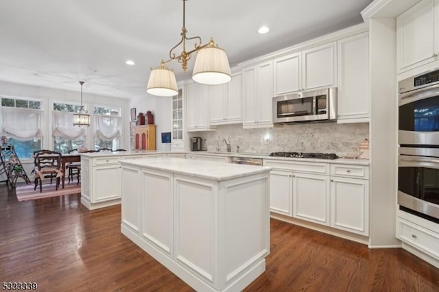 kitchen with appliances with stainless steel finishes, decorative light fixtures, kitchen peninsula, and white cabinets