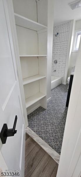 bathroom with tiled shower / bath and wood-type flooring