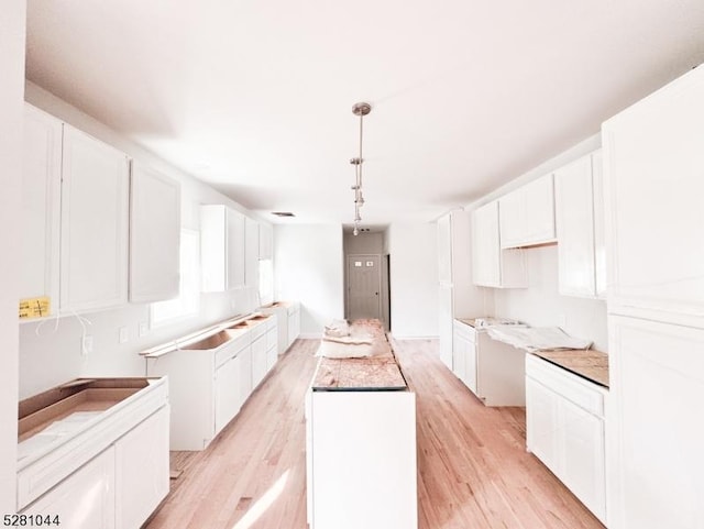 kitchen with white cabinets, visible vents, light wood-type flooring, and pendant lighting