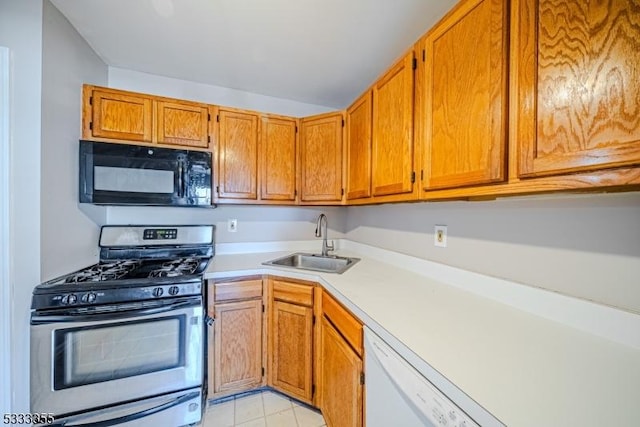 kitchen featuring stainless steel gas range oven, sink, white dishwasher, and light tile patterned flooring