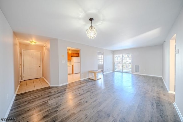 unfurnished living room with wood-type flooring and a notable chandelier