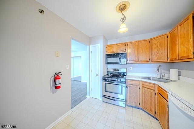 kitchen featuring dishwasher, stainless steel gas range oven, sink, and pendant lighting