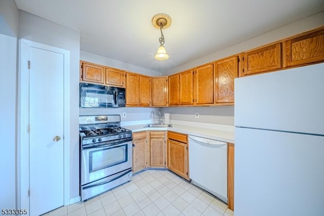 kitchen featuring decorative light fixtures, sink, and white appliances